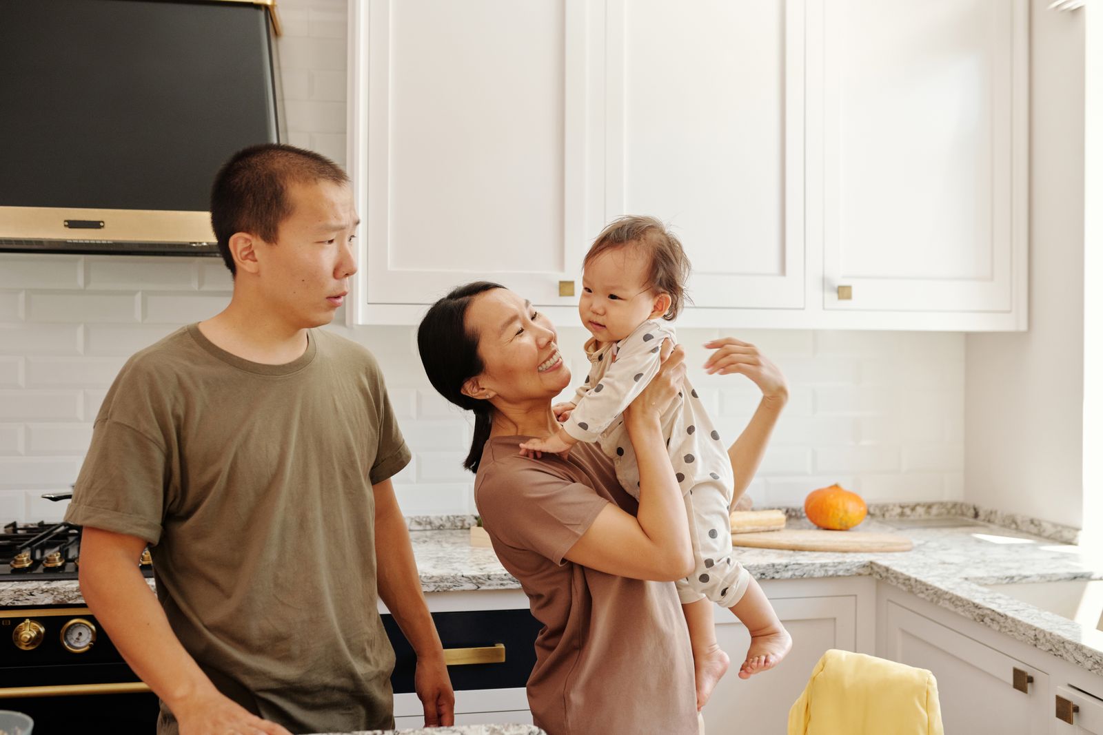A mother and father playing with their baby in the kitchen