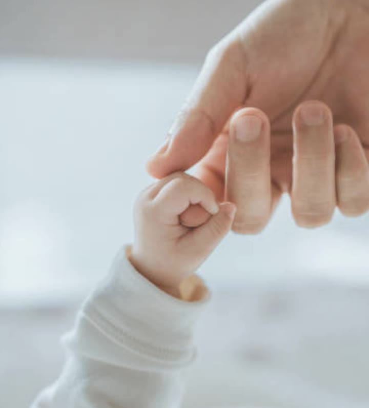 A baby's hand gently holding a parent's finger