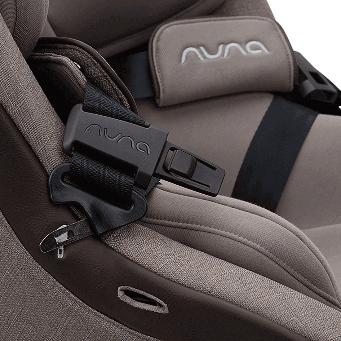 Close-up of the Nuna REVV maxx Cedar magnetic buckle holder keeping a harness strap open, with a padded Nuna chest pad and leatherette trim