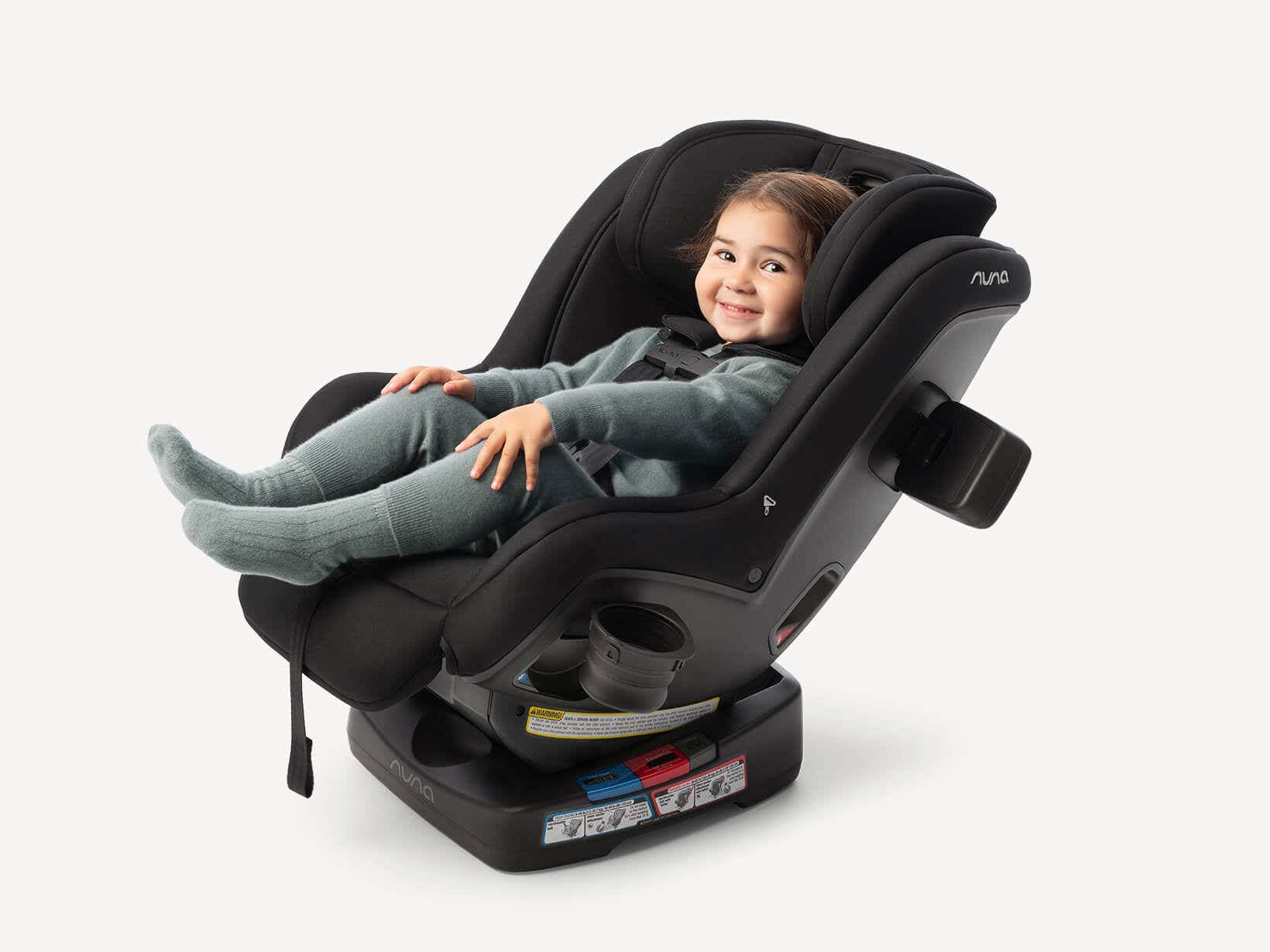 Toddler sitting reclined and rear-facing in the Nuna RAVA next with legs comfortably raised