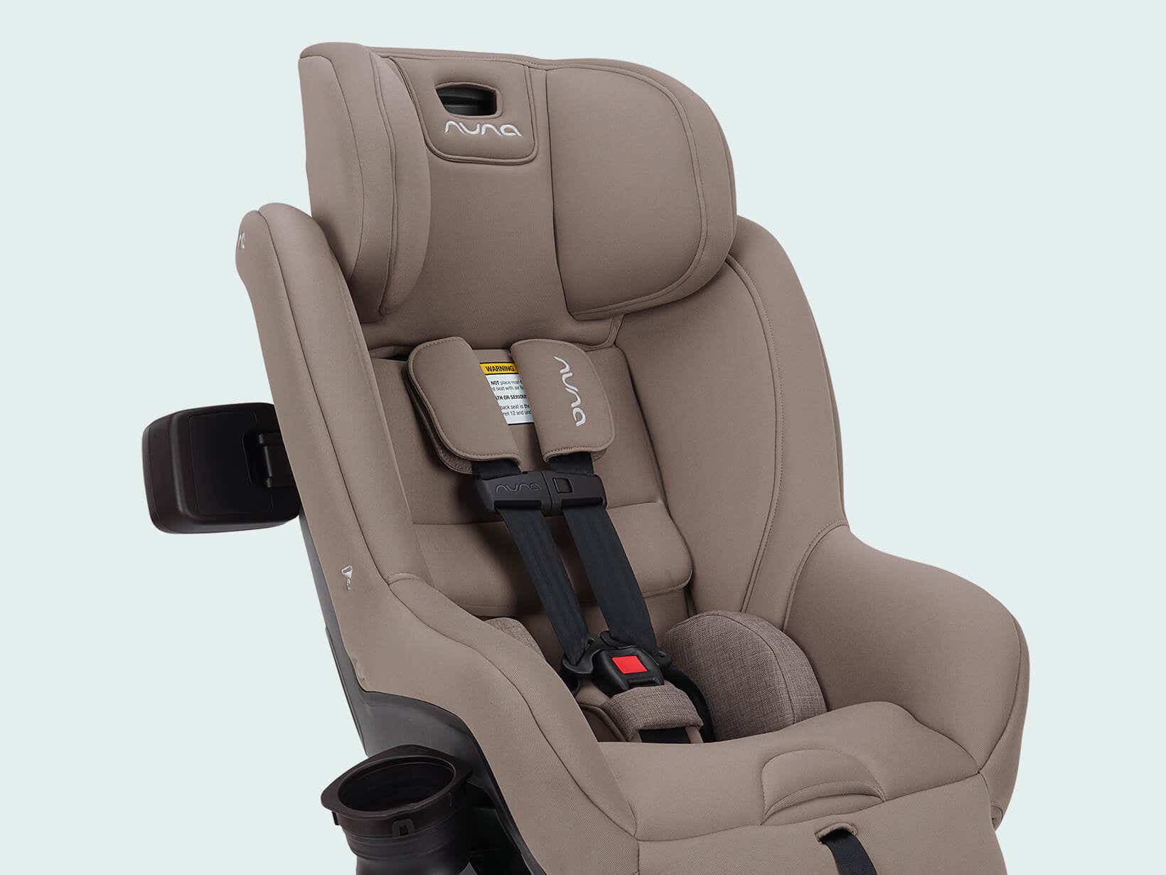 Close-up of the Nuna RAVA next no-rethread 5-point harness with magnetic chest pads and buckle on taupe fabric